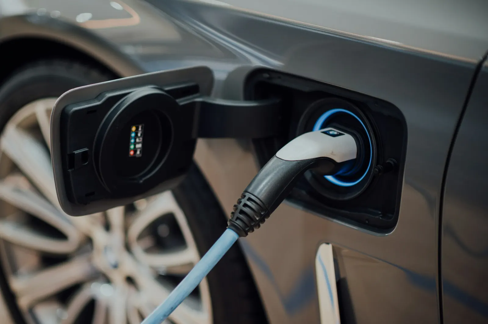 Close-up of a charging cable plugged into an electric vehicle's charging port, representing the new set of questions EV shoppers bring to the car-buying journey.