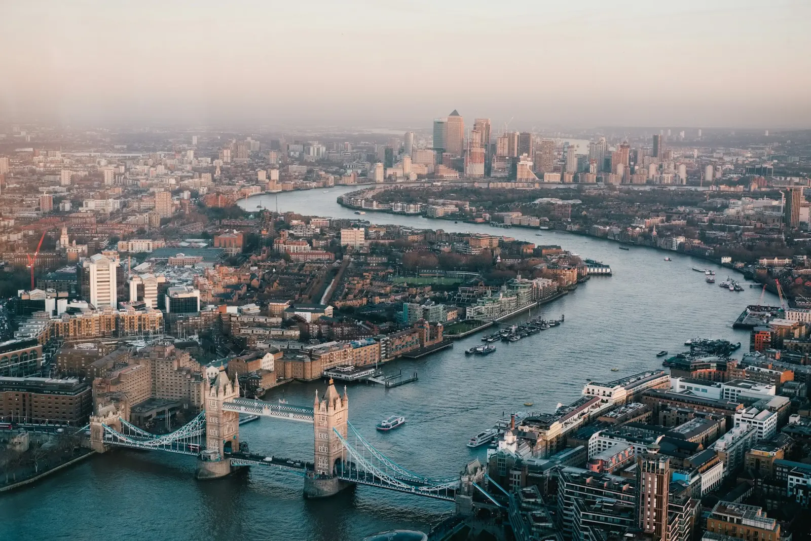 Aerial view of London at dusk with Tower Bridge and the River Thames winding towards Canary Wharf, representing UK brands competing under a new wave of customer-facing regulation.