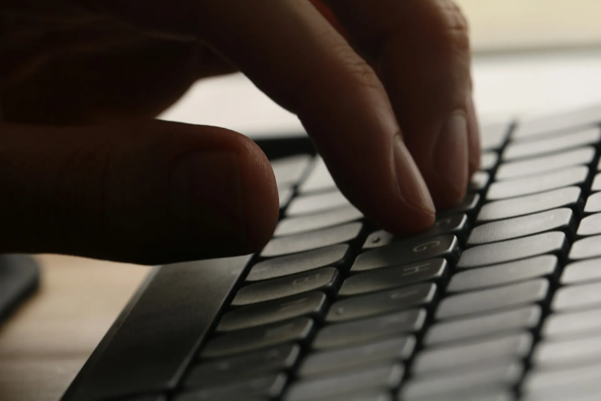 A close-up of a hand pressing the keys of a dark keyboard, representing a customer completing an online journey with a keyboard alone.