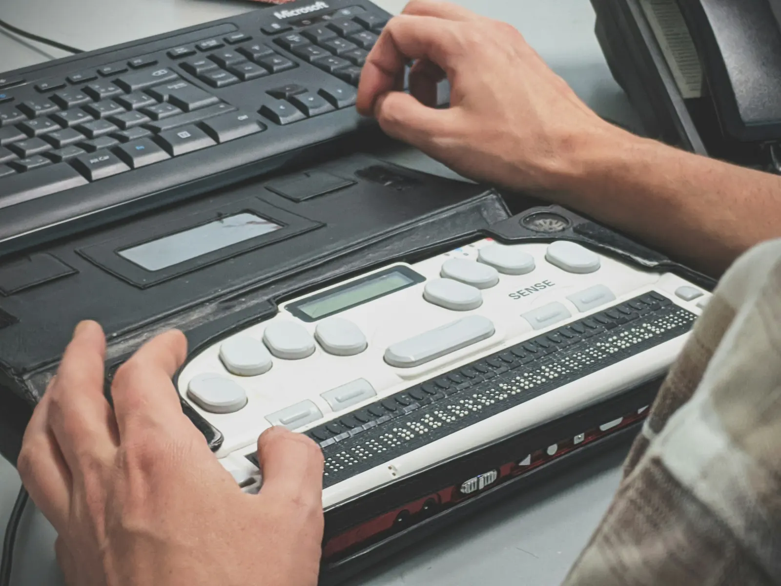 A person's hands on a refreshable braille display in front of a computer keyboard, the kind of assistive technology millions of EU customers use to shop, bank and book online.
