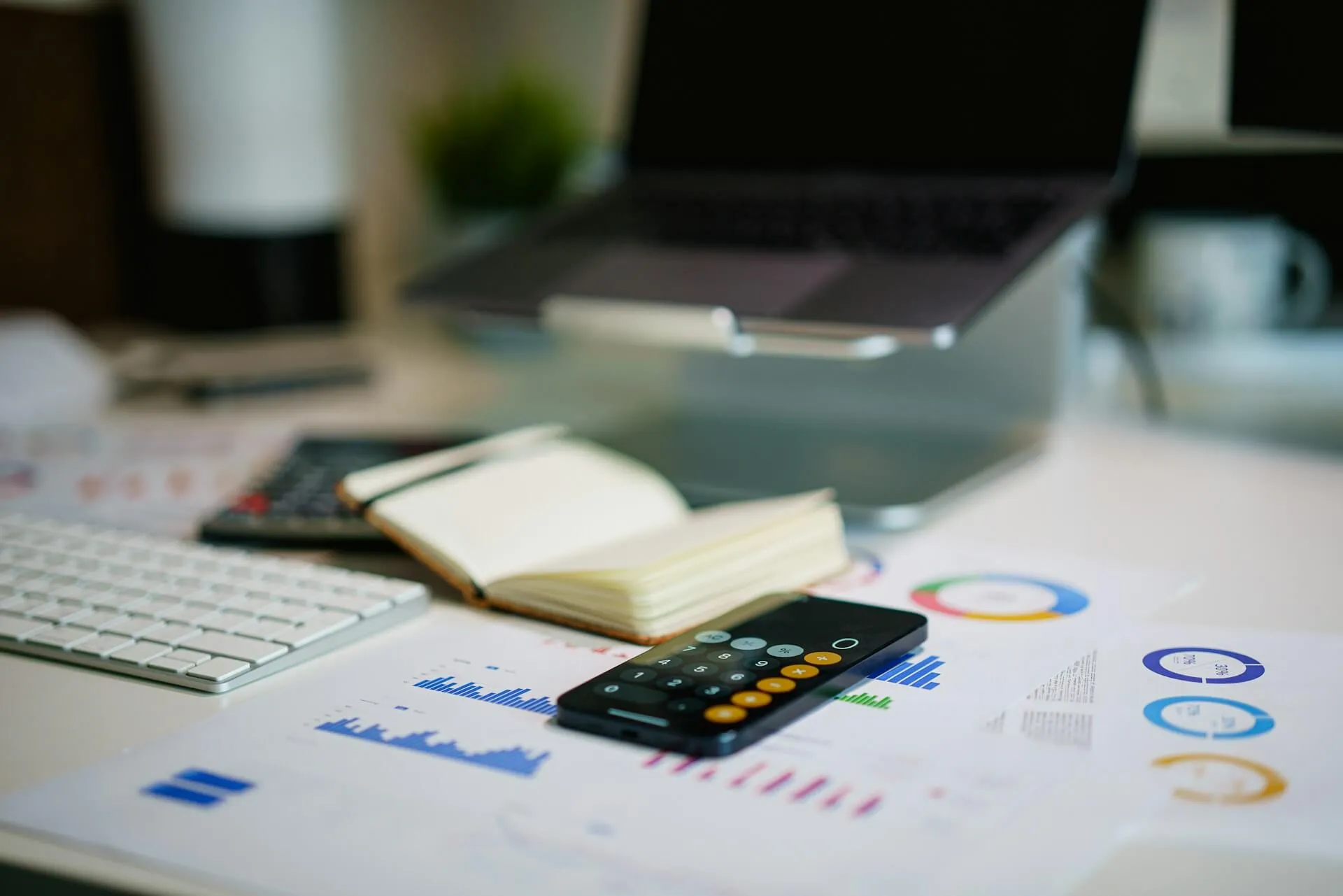 Office desk with smartphone and financial charts, representing business performance measurement and UX ROI tracking.